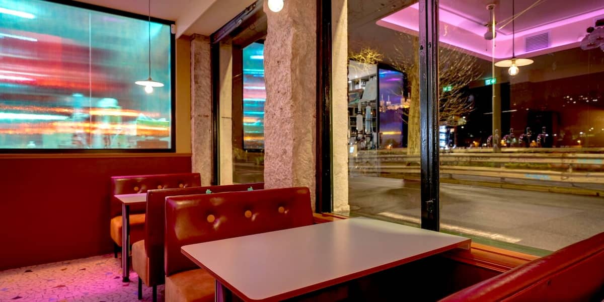 Banquettes du bar Abstract à Lyon près des grandes fenêtres et des panneaux lumineux colorés