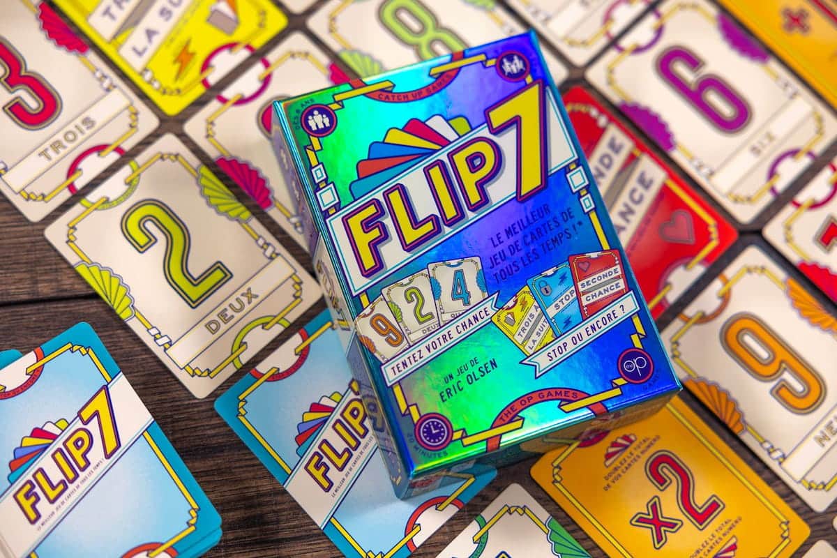 Boîte du jeu Flip 7 de Catch Up Games entourée de cartes colorées sur une table.