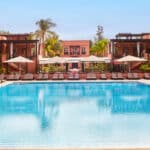 Piscine du Naoura Marrakech, hôtel Barrière situé près de la médina, avec façades ocres, transats et palmiers.