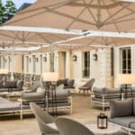 Terrasse Andy du Dolce Versailles avec parasols, salons extérieurs et tables installées dans un cadre verdoyant près de Paris