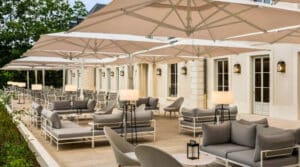 Terrasse Andy du Dolce Versailles avec parasols, salons extérieurs et tables installées dans un cadre verdoyant près de Paris