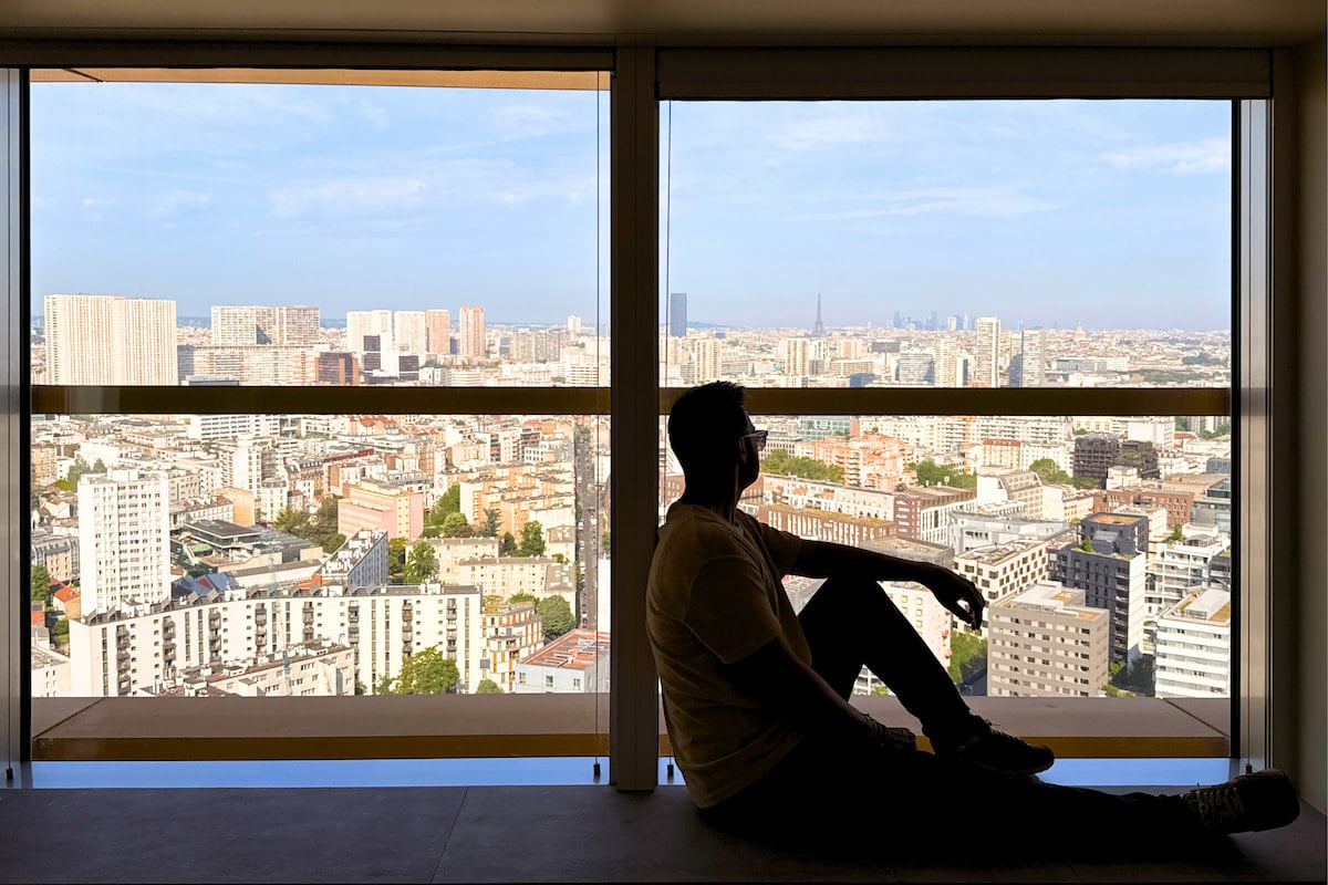 Une personne assise face à la vue panoramique sur Paris depuis une suite du TOO Hôtel