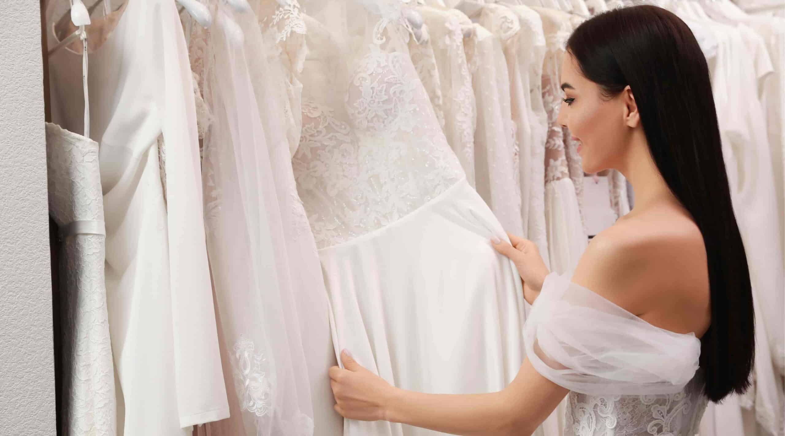 Jeune femme essayant une robe de mariée dans un salon