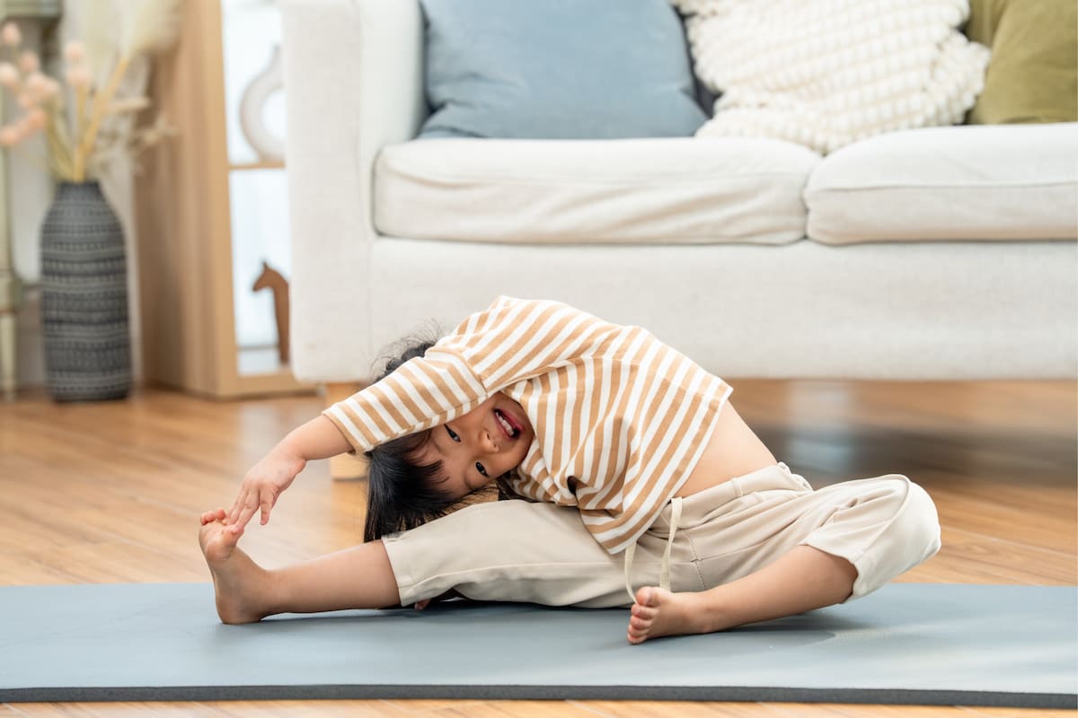 Une femme réalise un étirement sur un tapis de yoga dans son salon.