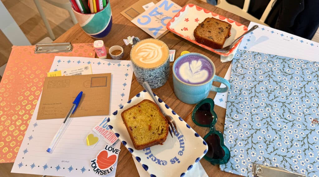 Une table du Café Pli à Paris avec lettres, cartes, stickers, boissons et gâteaux pour écrire à son futur soi