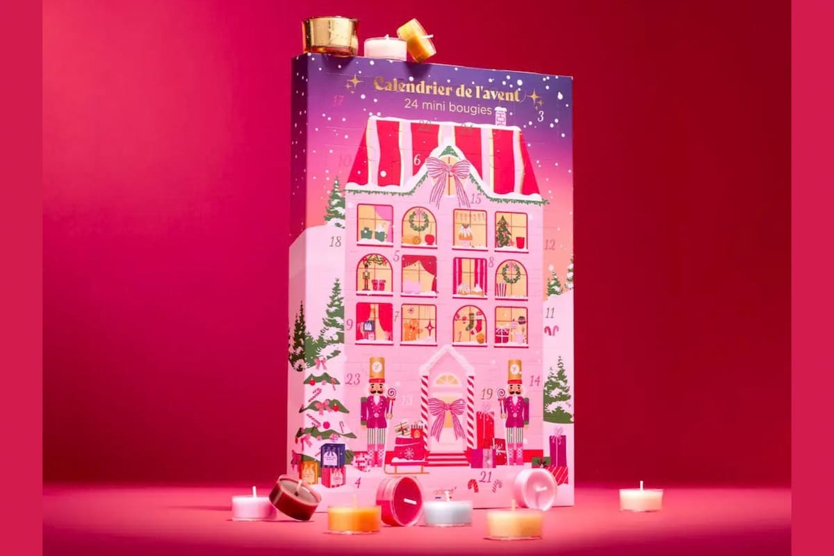 Calendrier de l'Avent Adopt 2026 en forme de maison de Noël rose, entouré de mini-bougies parfumées.