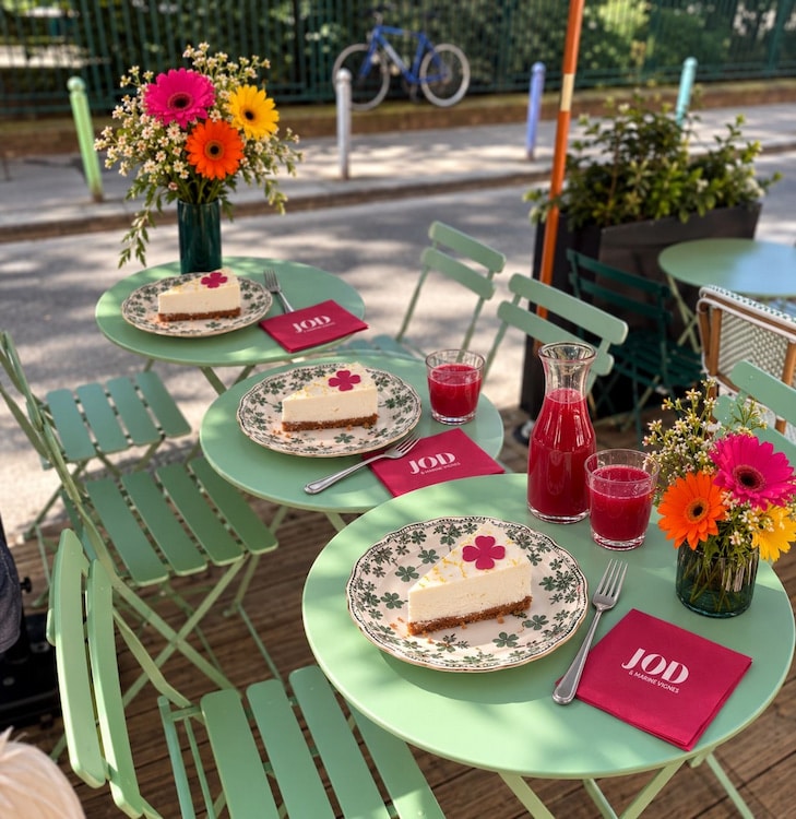 Terrasse du Grace Café à Paris avec des cheesecakes maison, des boissons rouges et des bouquets de fleurs pour la collaboration JOD x Marine Vignes