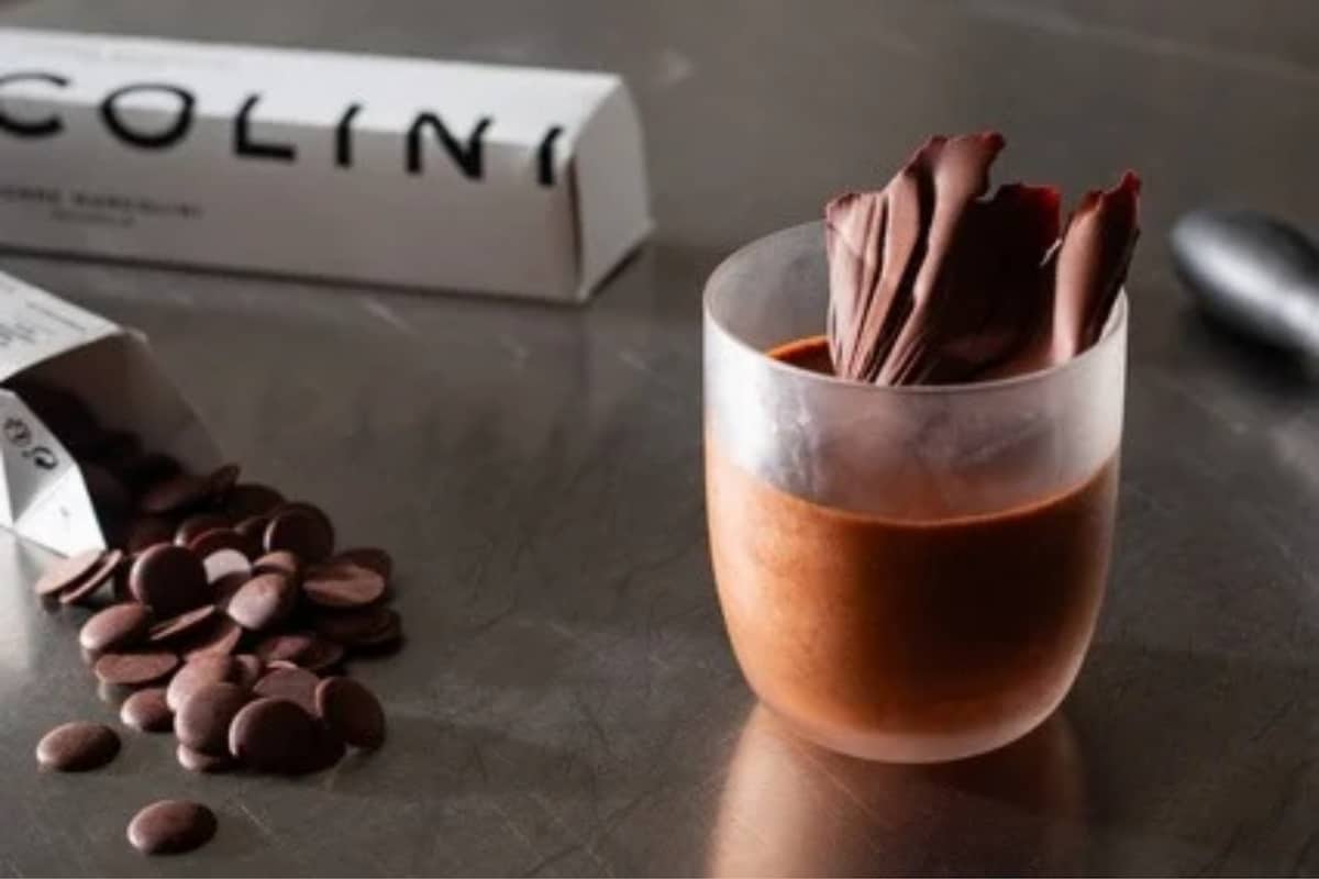 Chocolat à cuisiner Pierre Marcolini avec pistoles de chocolat et préparation chocolatée dans un verre.