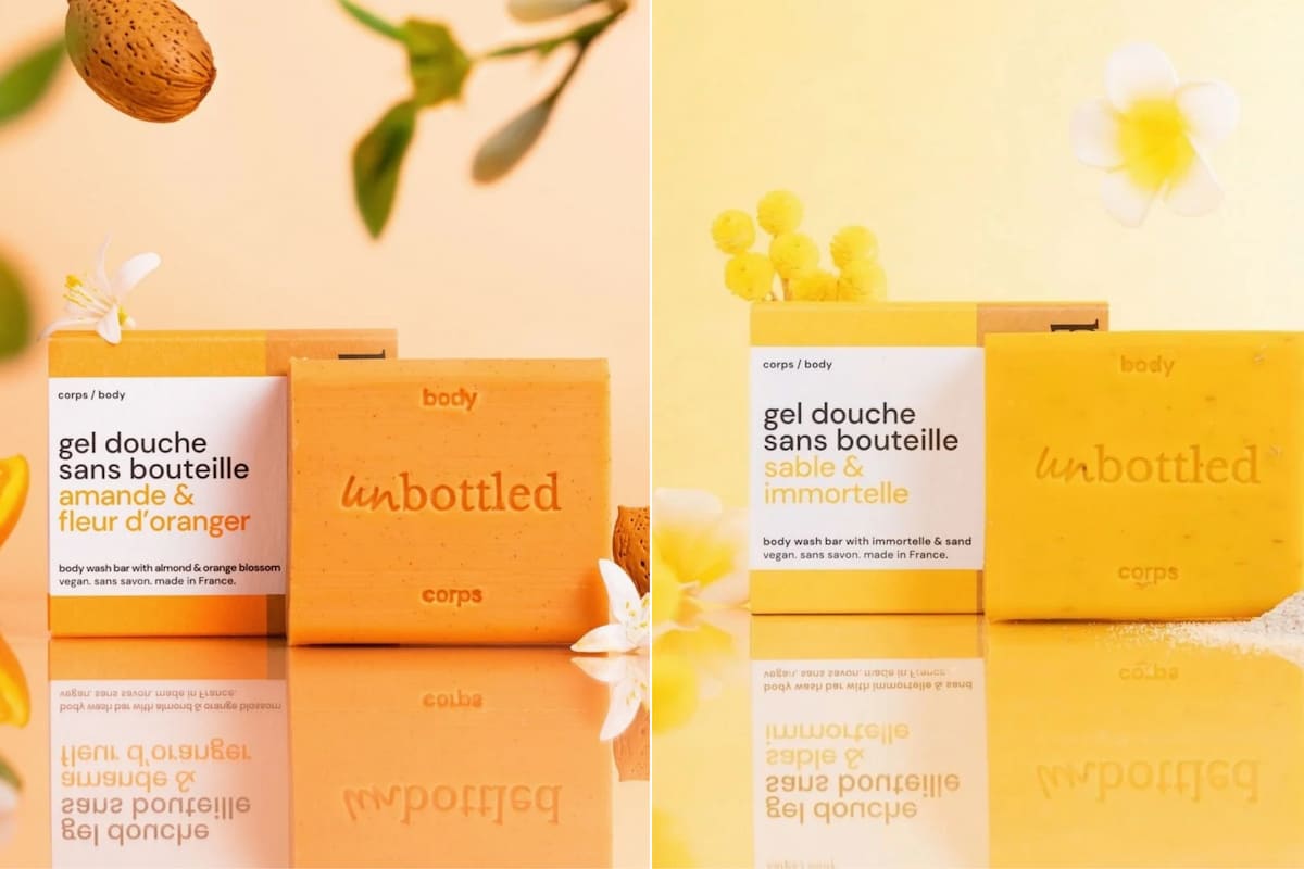 Gels douche solides Unbottled aux senteurs Amande & Fleur d'Oranger et Sable & Immortelle, accompagnés de leurs emballages.
